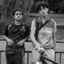 A black and white photo of two teenage boys leaning against a railing looking at the camera.