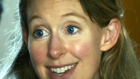 Close-up portrait of a smiling woman with blue eyes and long brown hair.
