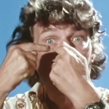 A close up photo of a man pointing at his eye.