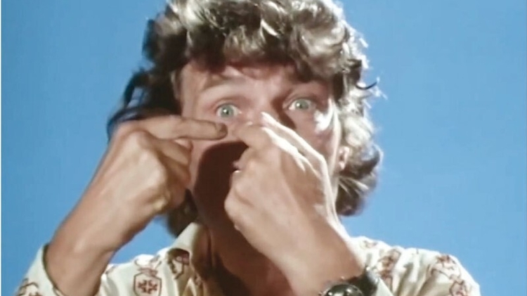 A close up photo of a man pointing at his eye.