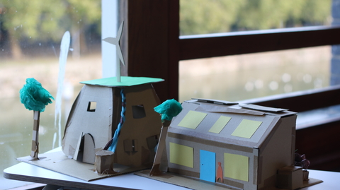 A paper model of two homes positioned on a table overlooking the Harbourside in the background.