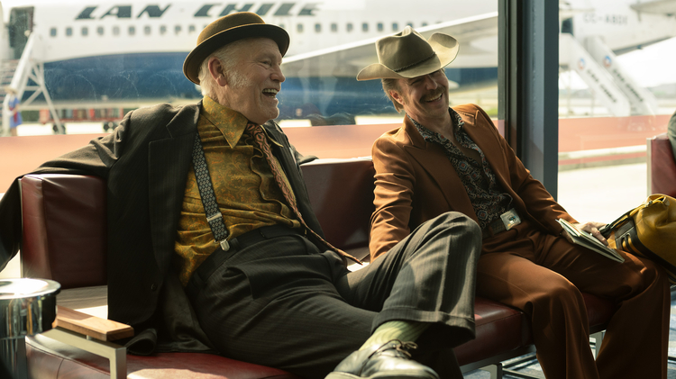 Two men in hats sitting next to each other.