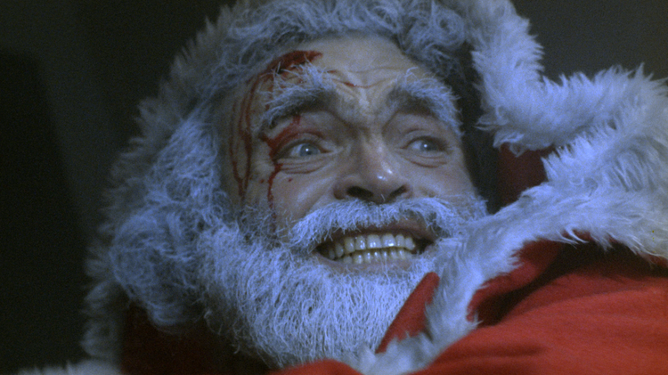 A close up photo of Santa Claus with blood on his head.