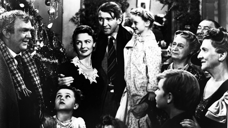 Black-and-white scene of a family gathered around a decorated Christmas tree, with adults and children sharing a festive moment.