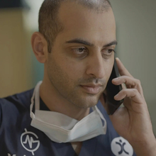 A doctor holding a mobile phone up to his ear.