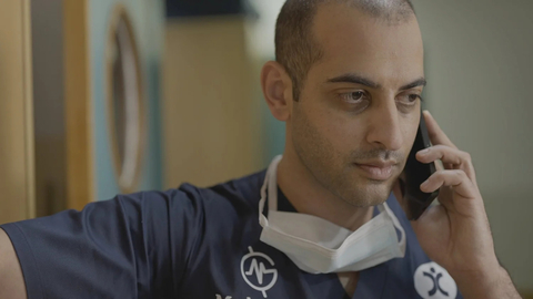 A doctor holding a mobile phone up to his ear.