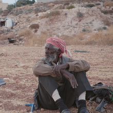 A man sitting on the ground outside.
