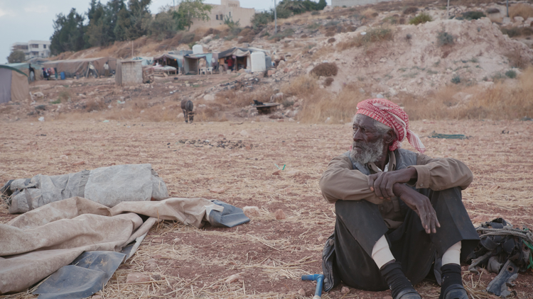 A man sitting on the ground outside.