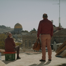 Two men standing outside looking out across a city.