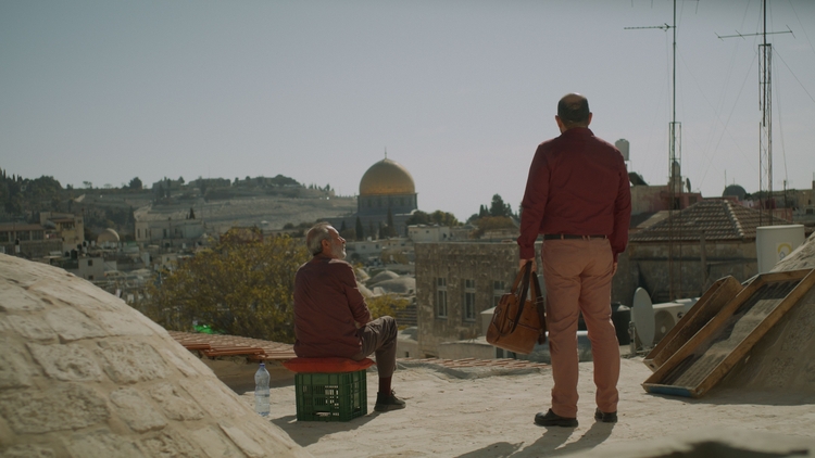 Two men standing outside looking out across a city.
