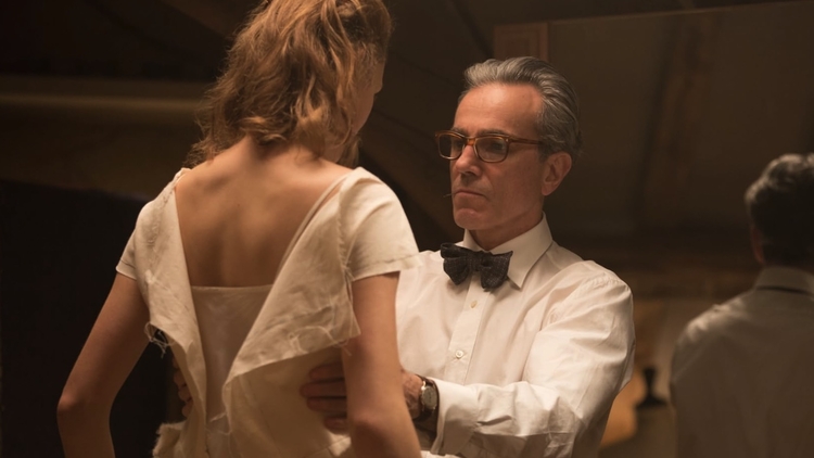 Man in glasses and bow tie holds a woman in a white dress during a warmly lit dance scene.