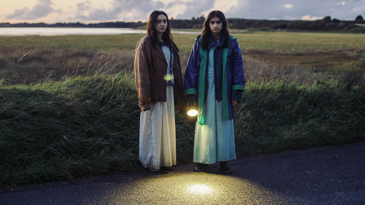 A still from the film September Says showing two sisters standing in a field