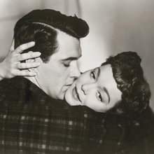 A close embrace between two people, showcasing intimacy with hands gently touching, set against a soft-focus background.