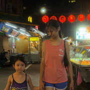 A still from the film Left-Handed Girl showing a woman and child walking through a night market in Taipei holding hands.