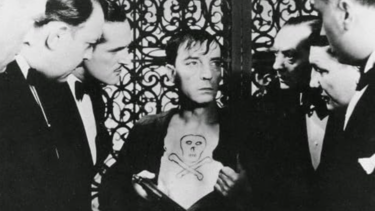 An gathering of elegantly dressed individuals, against an ornate ironwork background.