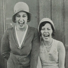 Two women holding hands laughing out loud.