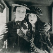 A man and woman cling to each other tightly, looking into the distance.