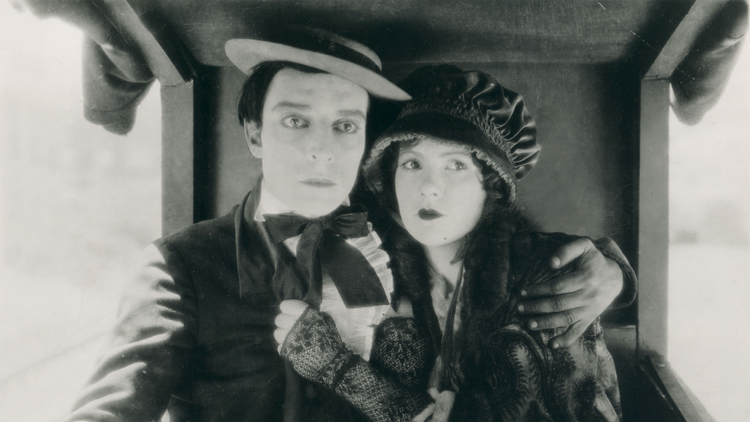 A man and woman cling to each other tightly, looking into the distance.