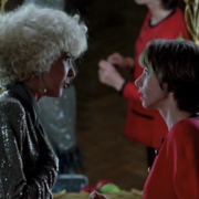 Two women engage in conversation in front of a vintage mirror, accentuated by elegant lighting and retro-style decor.