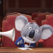 A chameleon wearing a hat uses a megaphone, while a surprised koala in a tuxedo sits at a desk in a theatre.