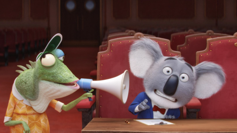 A chameleon wearing a hat uses a megaphone, while a surprised koala in a tuxedo sits at a desk in a theatre.