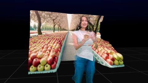 An image of a woman wearing a white t shirt and blue jeans, rendered in a 3D environment, surrounded by two separate shelves of apples, with an apple orchard in the background. She is smiling, looking off camera to the right. 