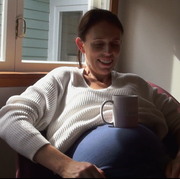 A still from the film Prime Minister of Jacinda Ardern resting a mug on her pregnant stomach