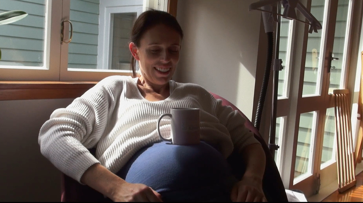 A still from the film Prime Minister of Jacinda Ardern resting a mug on her pregnant stomach