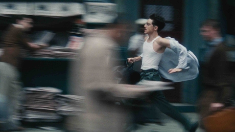 A man in a white tank top runs through a busy street, papers flying around him, creating a sense of urgency and motion.