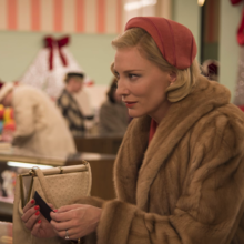 Two women in vintage holiday attire converse in a festive store, surrounded by Christmas decorations and shoppers.