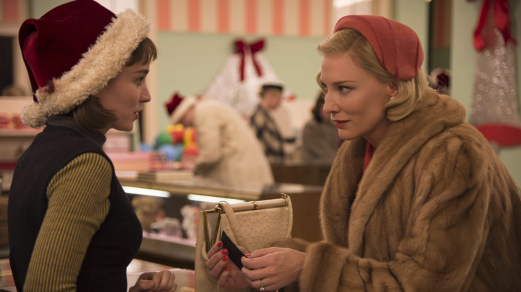 Two women in vintage holiday attire converse in a festive store, surrounded by Christmas decorations and shoppers.