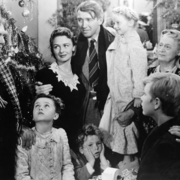 A black-and-white family gathering around a decorated Christmas tree, celebrating joyfully amidst holiday decorations and gifts.