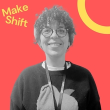 Jaz is a Smiling person with curly hair and glasses in grayscale, wearing a sweater with a large apple design and a lanyard. Bold red background with "Make Shift" text.