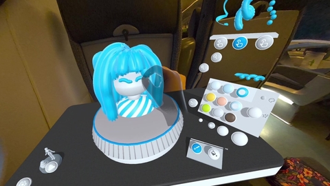 A screenshot from Taru Muhonen's app, Spira - the image depicts a digital render of the app in use; in the centre of the shot, a transparent hand, controlled by the user, fixes a bust with a white face and blue hair. To the right of the bust is a white controller with multi coloured buttons. The bust and controller sits on a black tabletop. 