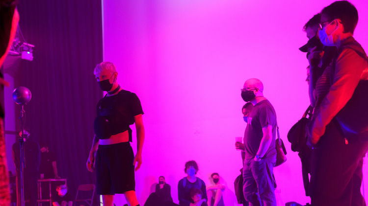 People in black clothes, wearing masks and breathing.systems equipment on their chests. The lighting is dimmed, purple and pink. 