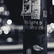 A black and white image of a lamp post with text written on it - the text reads "Big Data is Watching You", and is written on the lamp post with white ink on the black structure. 