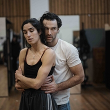 Two people rehearsing in a studio with wooden floors and mirrors.