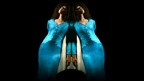An image of the voice artist Angelica Allen. She is posing in the centre of the image, and is mirrored, creating a rorschach-test like image of two Angelicas side by side, seemingly leaning on each other. 