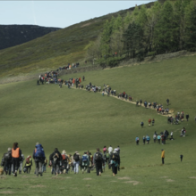 A still from Our Land of people walking up a hill