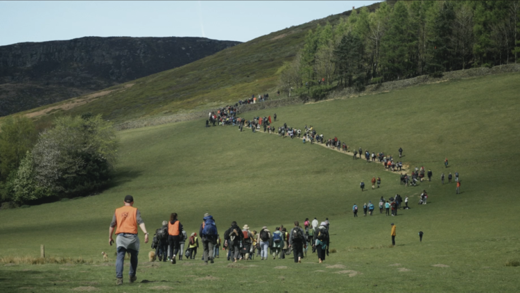 A still from Our Land of people walking up a hill