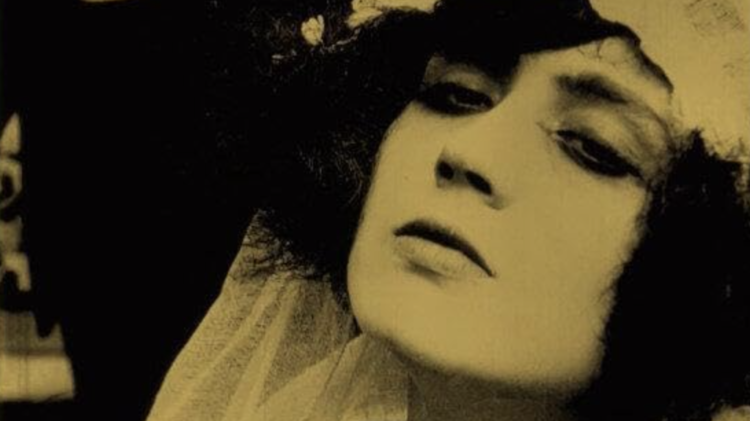 Sepia-toned close-up of a person wearing a textured garment, with dark background and partially visible hair and shoulder.