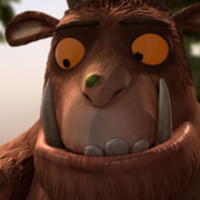 Animated large furry creature with big tusks holds a small smiling mouse on its hand in a forest setting.