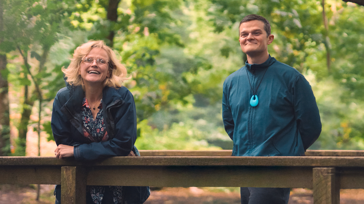 A still from the film I Swear of a man and a woman leaning on a fence.