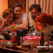 A still from Fairyland of a girl blowing out the candles on a cake surrounded by people.