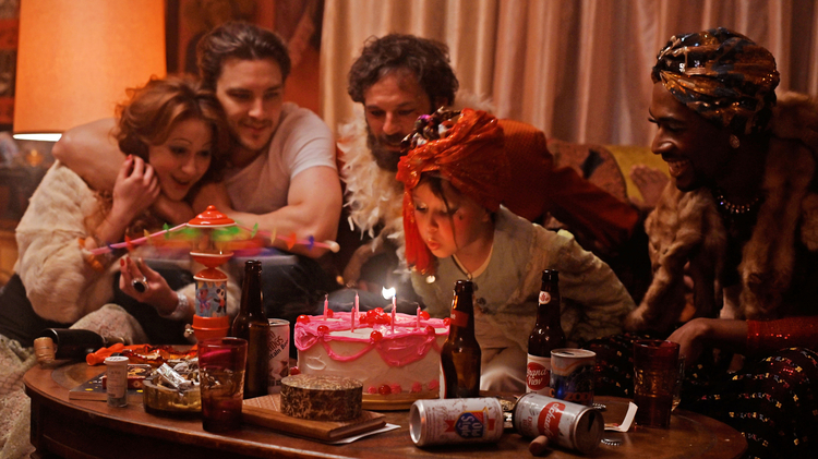 A still from Fairyland of a girl blowing out the candles on a cake surrounded by people.