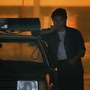 A still from As Tears Go By of a person leaning against a police car, set against a glowing orange background.