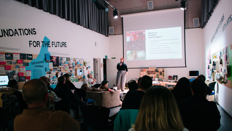 An image of Coral Manton giving a talk on the role of the Creative Technologist to a large audience. 