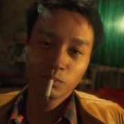 A still from Happy Together of a man looking directly at the camera with a cigarette in his mouth.