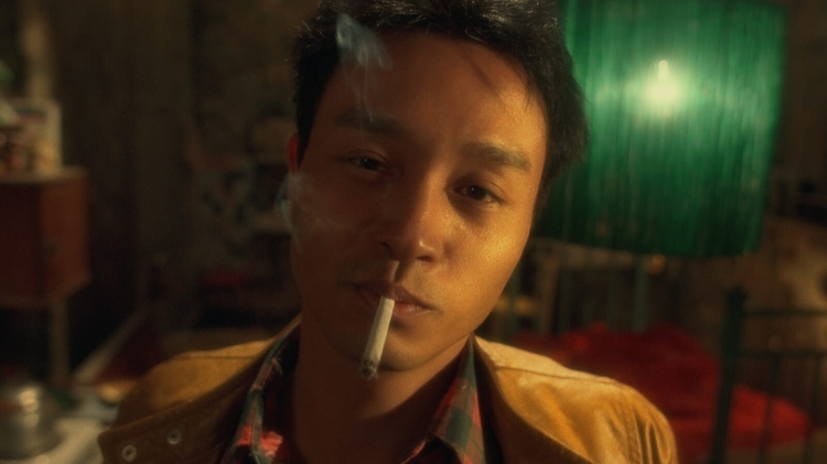 A still from Happy Together of a man looking directly at the camera with a cigarette in his mouth.