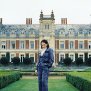 A still from Lady of a person standing outside a country manor is a tartan suit.